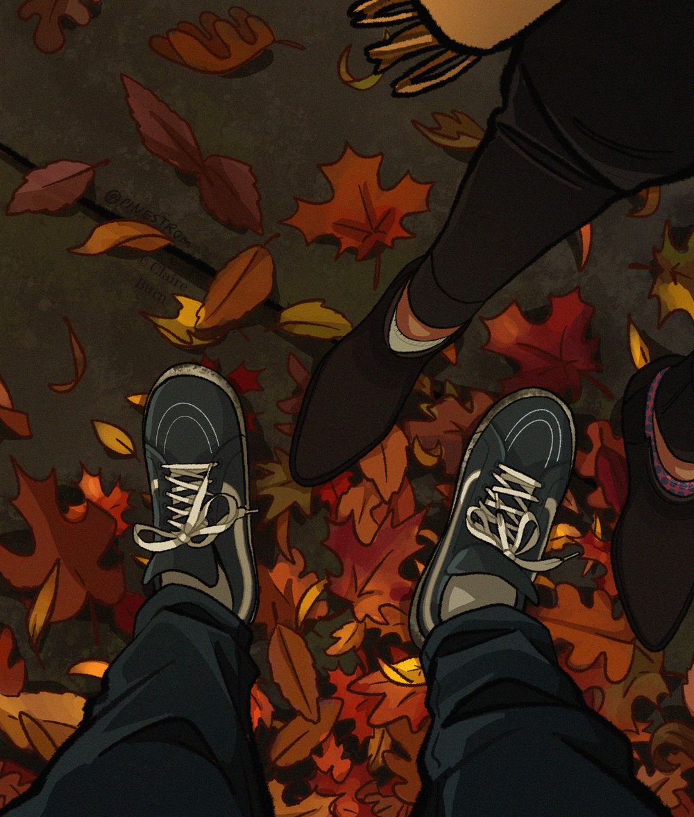 Downward view of two people's feet, standing on a sidewalk covered in autumn leaves.